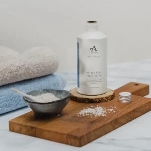 Arran Naturals Mindful Bath Salts on wooden board beside folded towels