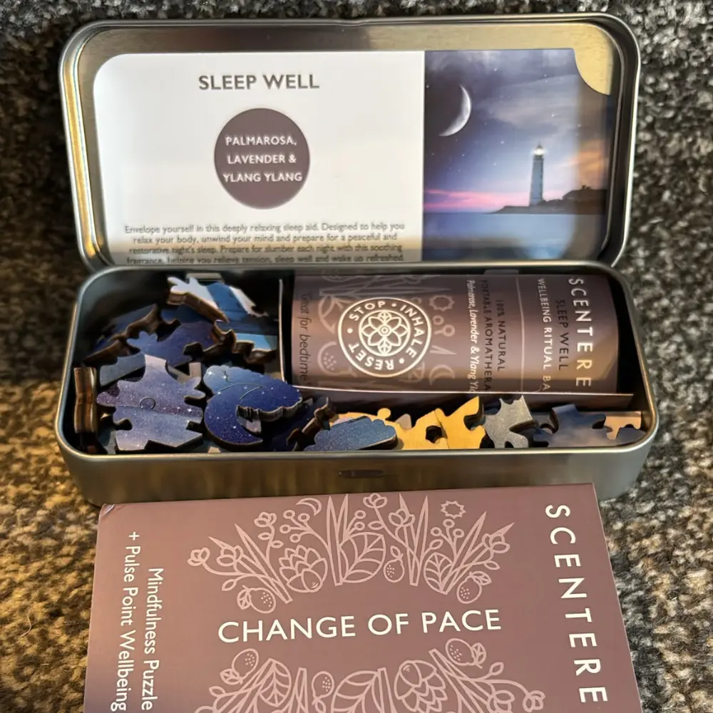 Open Scentered Sleep Well puzzle tin showing wooden pieces, balm and bedtime aromatherapy instructions